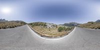 an image of a panoramic view of a road from underneath a curve with hills in the back ground