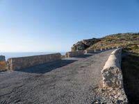 a paved stone walkway with an arch on the side of it with sea views in the distance