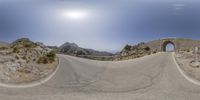 there is a panorama lens image of a curved road with the sun in the background