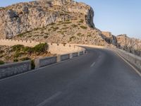 a lone motorcycle travels down an empty road near the seafront on the edge of a cliff