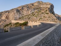 a lone motorcycle travels down an empty road near the seafront on the edge of a cliff