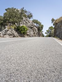 a man riding a motorcycle down the middle of a road with large rocks in the background