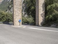 there is an empty road on the side of the bridge under some rocks and mountains