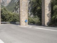 there is an empty road on the side of the bridge under some rocks and mountains