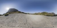 a fish eye view of a rocky mountain range with grass on the ground and mountains in the background