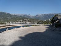 the road curves by the mountains over the ocean and mountains in the distance are filled with boats