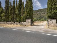 a empty road with a stone wall at the top and some trees on either side