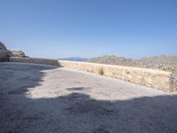 an asphalt surface with rocks and mountains in the background on a sunny day with no clouds