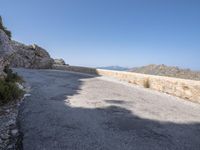 an asphalt surface with rocks and mountains in the background on a sunny day with no clouds