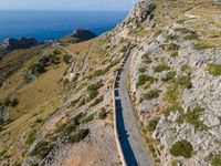 the curve road leads to an ocean view from a high cliff side overlook at rocky coastline and blue water