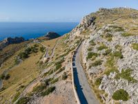 the curve road leads to an ocean view from a high cliff side overlook at rocky coastline and blue water