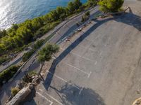 an aerial view of two tennis courts next to the water and on the shore with pine trees lining the walkway