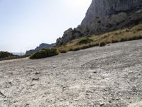 a lone bicycle is on a gravel road with mountains in the background and sky behind