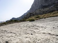 a lone bicycle is on a gravel road with mountains in the background and sky behind