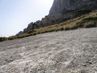 a lone bicycle is on a gravel road with mountains in the background and sky behind