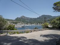 a street with lots of boats floating in the water near the mountains and a road