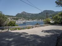 a street with lots of boats floating in the water near the mountains and a road