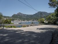 a street with lots of boats floating in the water near the mountains and a road