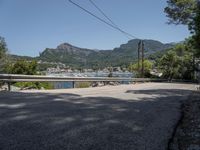 a street with lots of boats floating in the water near the mountains and a road