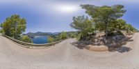 a fish eye view of a winding road in the mountains with a view of a lake