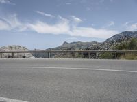 a person is riding their bike on a highway near the mountains with blue sky and a river