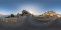 a wide angle view of a mountain and road from the top of a hill looking down onto some rocks