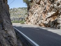 a motorcyclist driving along a mountainous road lined with rocks and boulderss