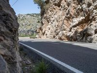 a motorcyclist driving along a mountainous road lined with rocks and boulderss