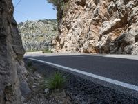 a motorcyclist driving along a mountainous road lined with rocks and boulderss