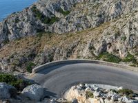 there is a small car on the road in the mountains near the ocean and water