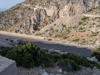 the view of a mountainous road is shown from above as motorcycles travel past it on the steep rocky mountaintop