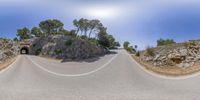 the long winding road curves past a hill in a beautiful natural environment and blue skies