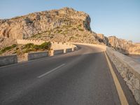 the road leads out onto a large cliff behind it and is empty at both sides of the road