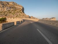 the road leads out onto a large cliff behind it and is empty at both sides of the road