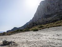 a person stands on a rocky cliff next to the ocean with some rocks and gravel below