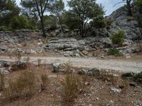 a dirt road going down a very steep mountain side side with rock formations in the background