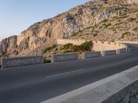 a motorcycle parked by a mountain cliff in italy that is the middle of the road