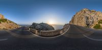 a 360 - camera lens view of a scenic road and mountains during the sunset with some water