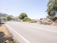 the road is paved and has several rocks along the side of it, including a steep hill