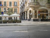 a sidewalk and sidewalk cafe near a street with umbrellas and tables on the corner