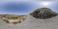 a mountain with a curved stone road near it and a car passing under a rock formation