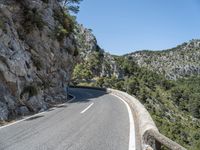 motorcycle rider on winding mountain pass with trees on both sides of road, overhead view