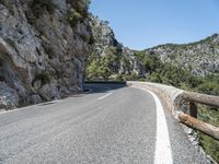 motorcycle rider on winding mountain pass with trees on both sides of road, overhead view