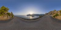 fish eye view of a winding road by the ocean with sunset in background from high angle lens