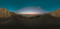 two winding roads that lead up to a desert area near the sun setting behind the horizon