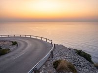 curved road with two traffic lanes at sunset overlooking the ocean and hills at sea side