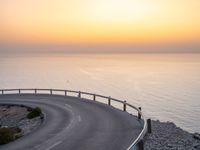 curved road with two traffic lanes at sunset overlooking the ocean and hills at sea side