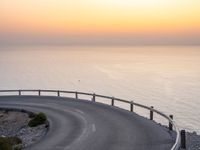 curved road with two traffic lanes at sunset overlooking the ocean and hills at sea side