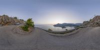 a fisheye lens view of a sunset over the ocean, a bridge and some cars