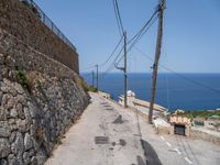 there is a stone wall that separates the street by the sea and two trucks are parked next to it